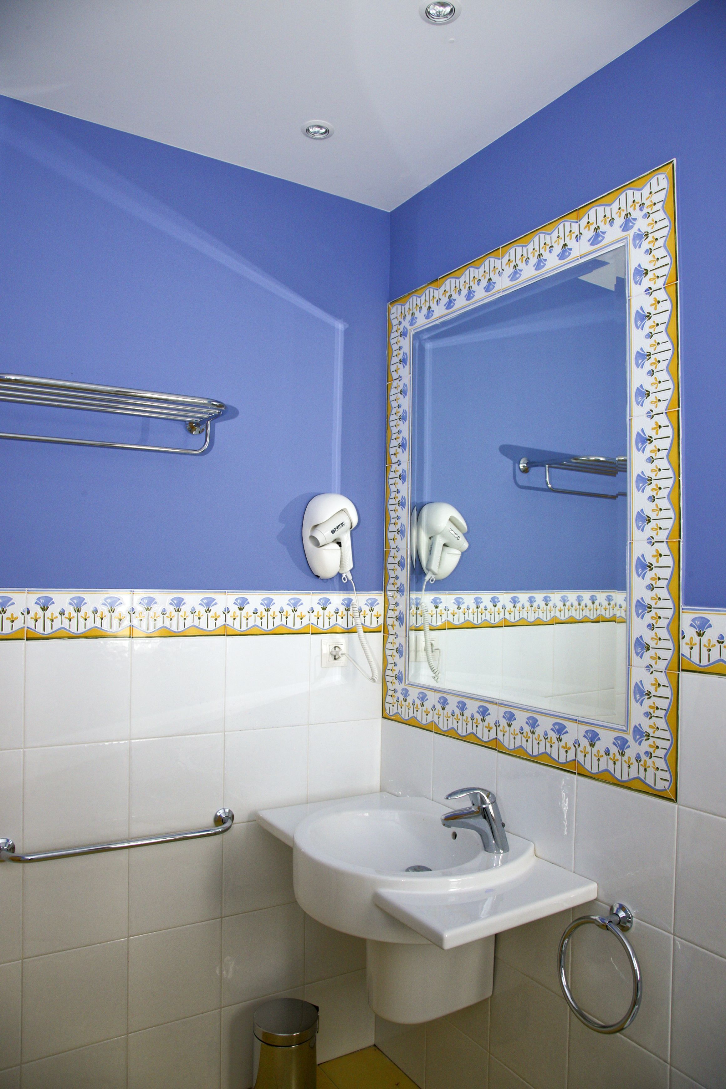 Un baño con lavamanos, espejo y toallero.