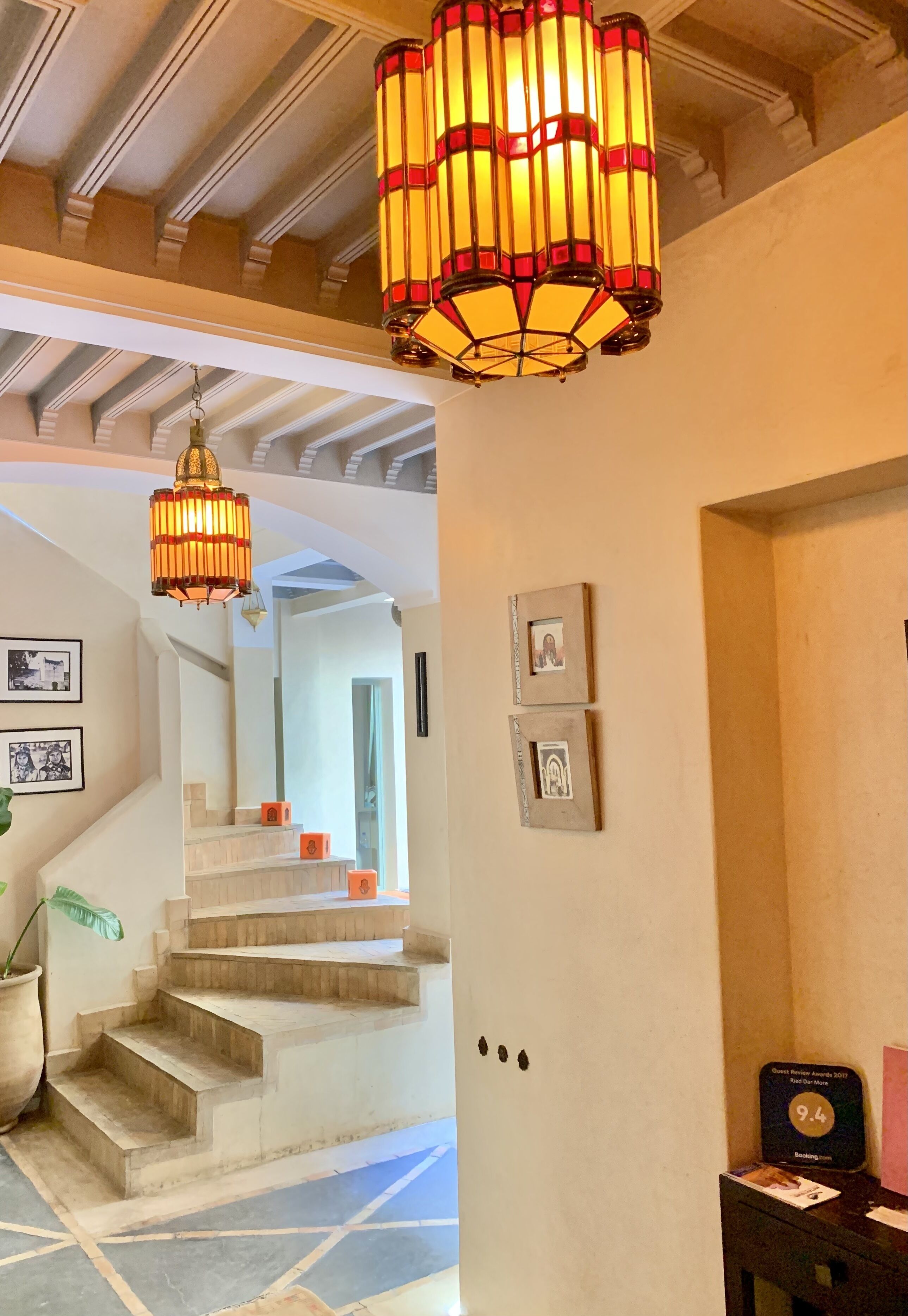 Una escalera de diseño moderno, un candelabro y cuadros enmarcados en la pared.