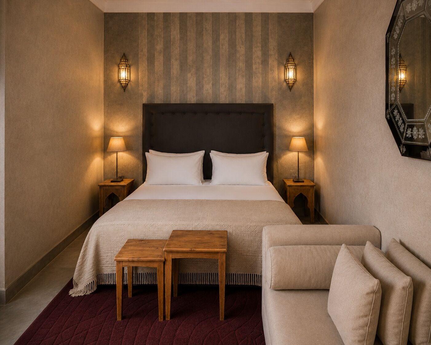 Quarto de hotel com uma cama grande, duas luminárias de cabeceira, uma mesinha e um sofá.