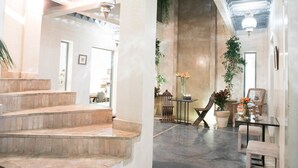 A spacious lobby with a staircase, a seating area with a table and chairs, and a large plant. - Riad Dar More (Marrakech)