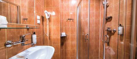 Un baño moderno con ducha acristalada, un lavabo blanco y un espejo.