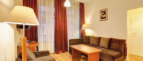 A living room with a sofa, a coffee table, a lamp, and a television.