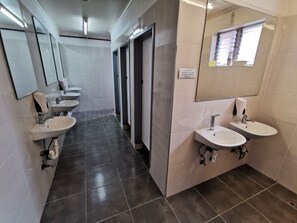 A modern bathroom with three sinks, a hand dryer, and a sign requesting cleanliness. - City Centre Budget Hotel (Melbourne)