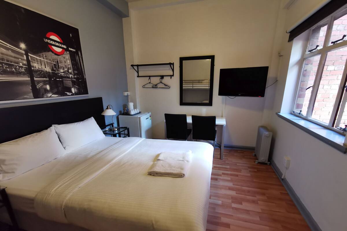 Une chambre d’hôtel avec un lit, un bureau, une chaise, une télévision et une fenêtre.