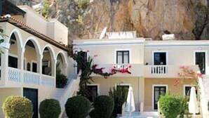 A pool area with a clear blue pool, surrounded by neatly trimmed bushes and a building with a white facade and arches. - Kyra Panaghia (Karpathos)