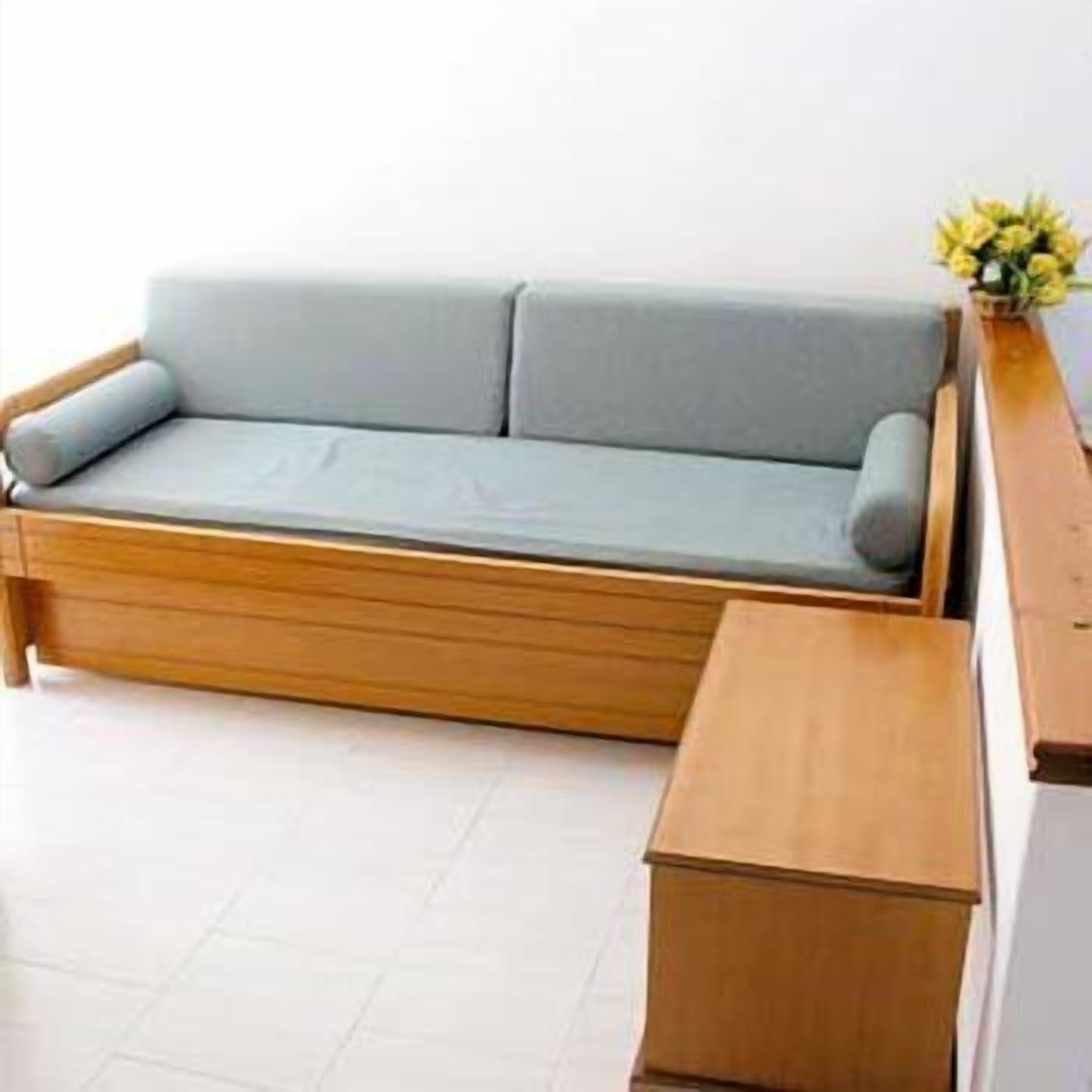 Un canapé bleu clair avec des pieds en bois et une table d’appoint assortie, également en bois.