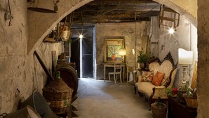 An arched doorway leading to a room with rustic decor, including a chair, a table, and various wicker baskets. - Palazzo Malaspina (Barberino Tavarnelle)
