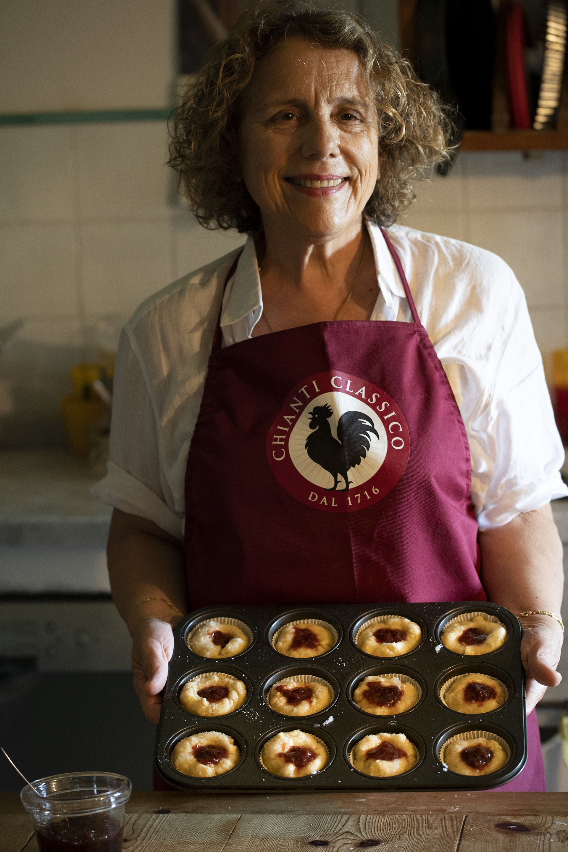 A person holding a muffin tray with baked goods.