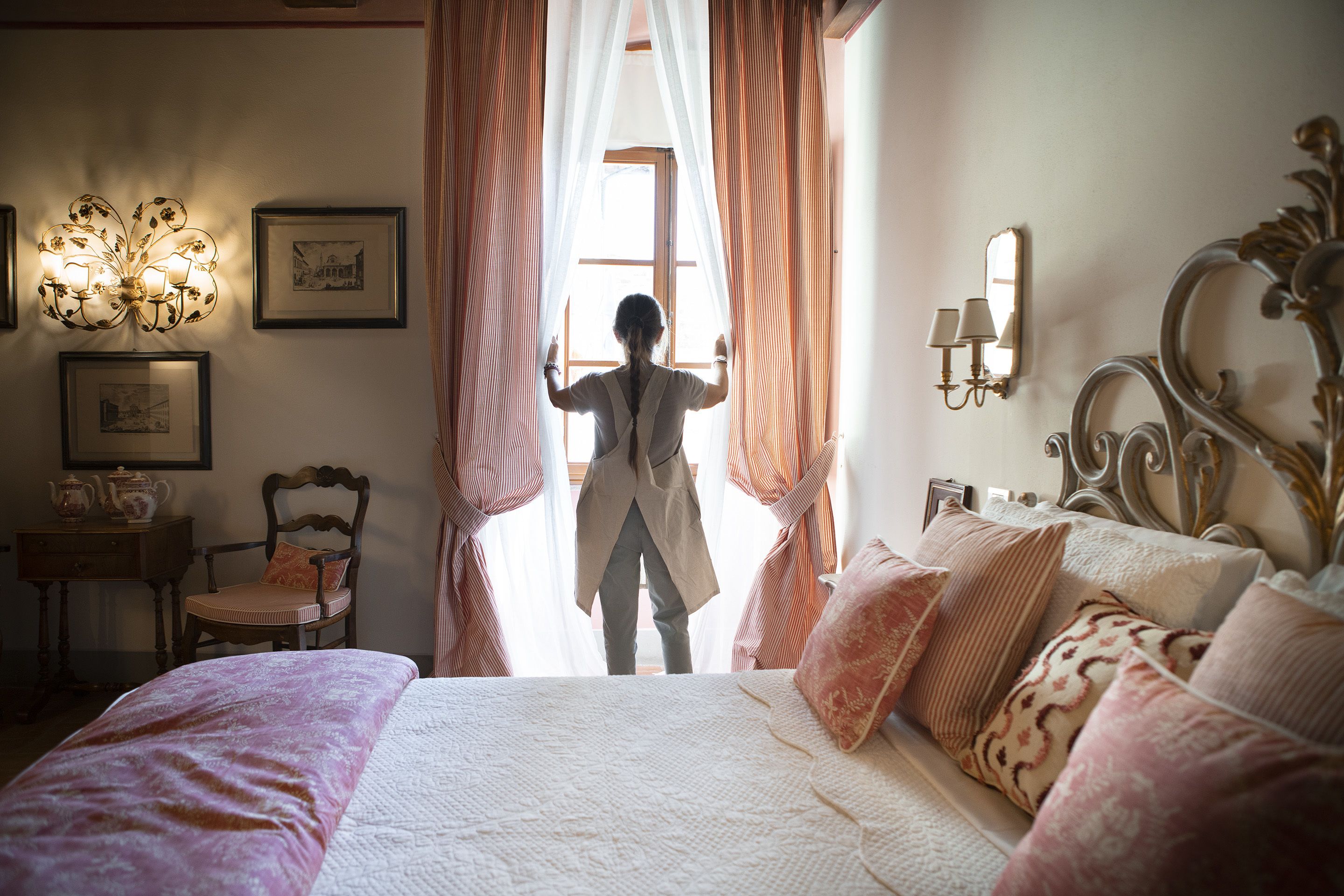 Een slaapkamer met een bed, een stoel, een bureau met een lamp en gordijnen.