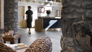 Un hall d’entrée avec des piliers en pierre, des meubles en osier et un comptoir d’accueil.
