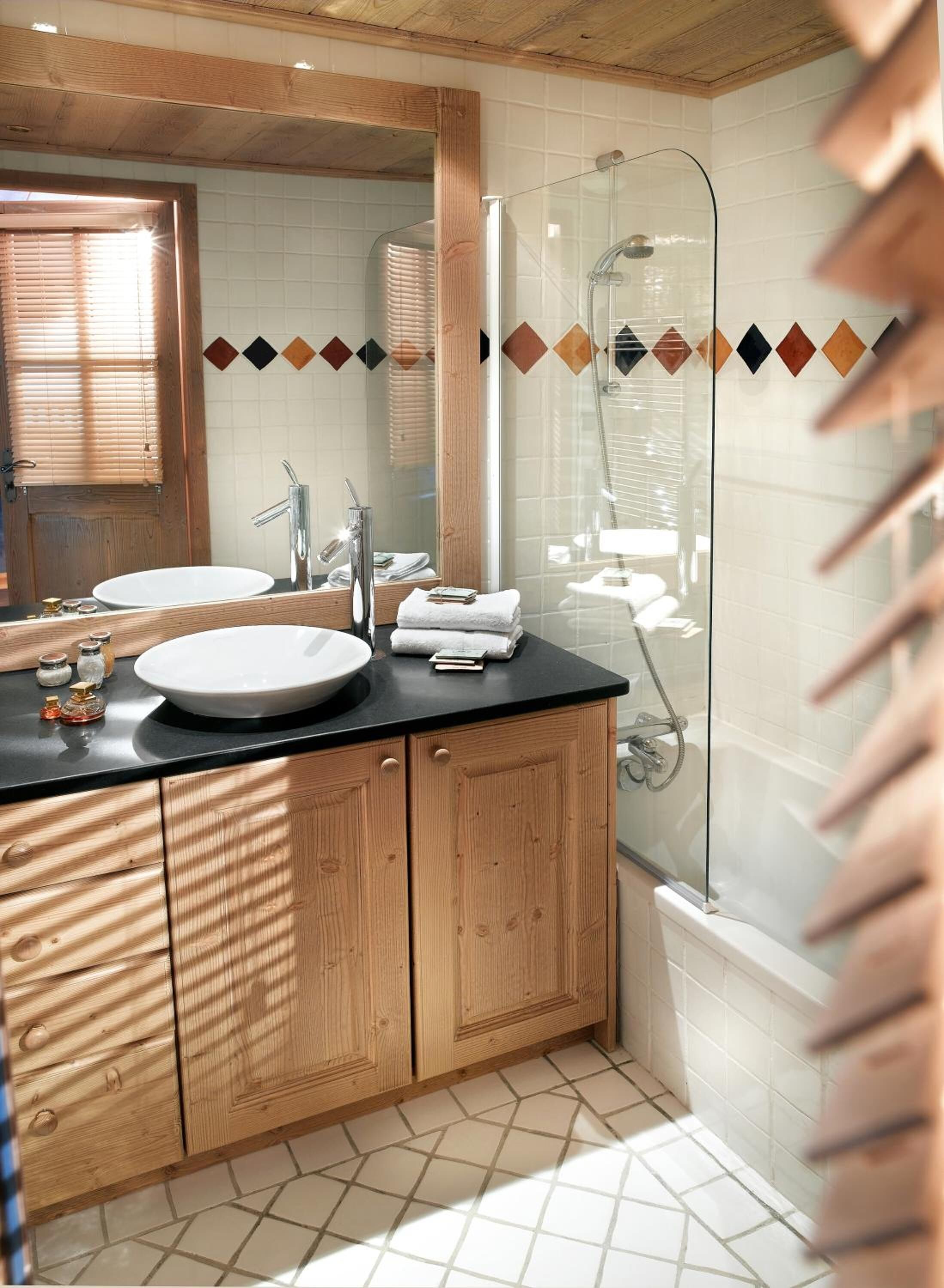A bathroom with a wooden vanity, two sinks, a large mirror, and a glass-enclosed shower.