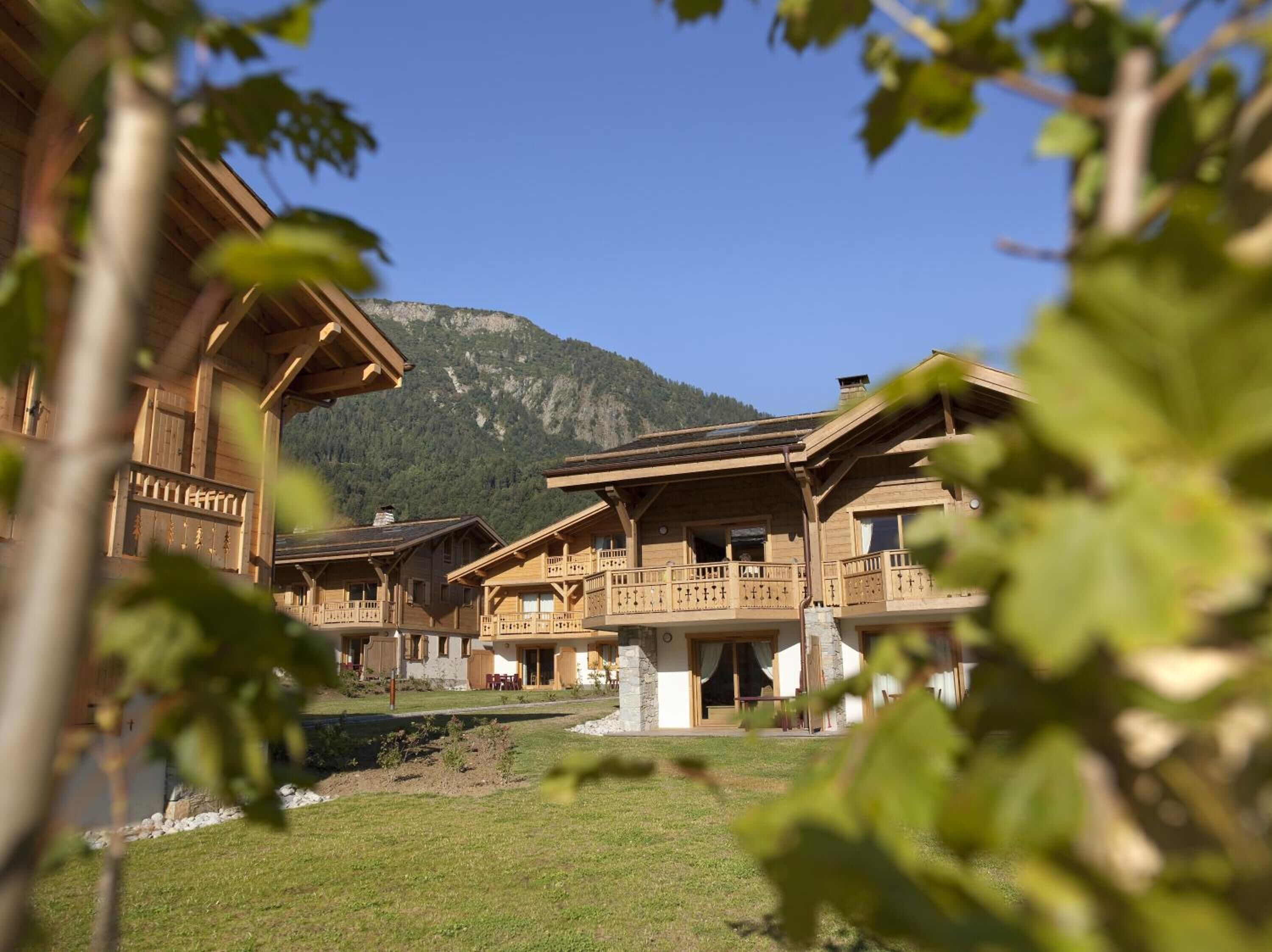 Un bâtiment de style chalet en bois, doté de balcons, qui se dresse sur un fond de paysage montagneux.