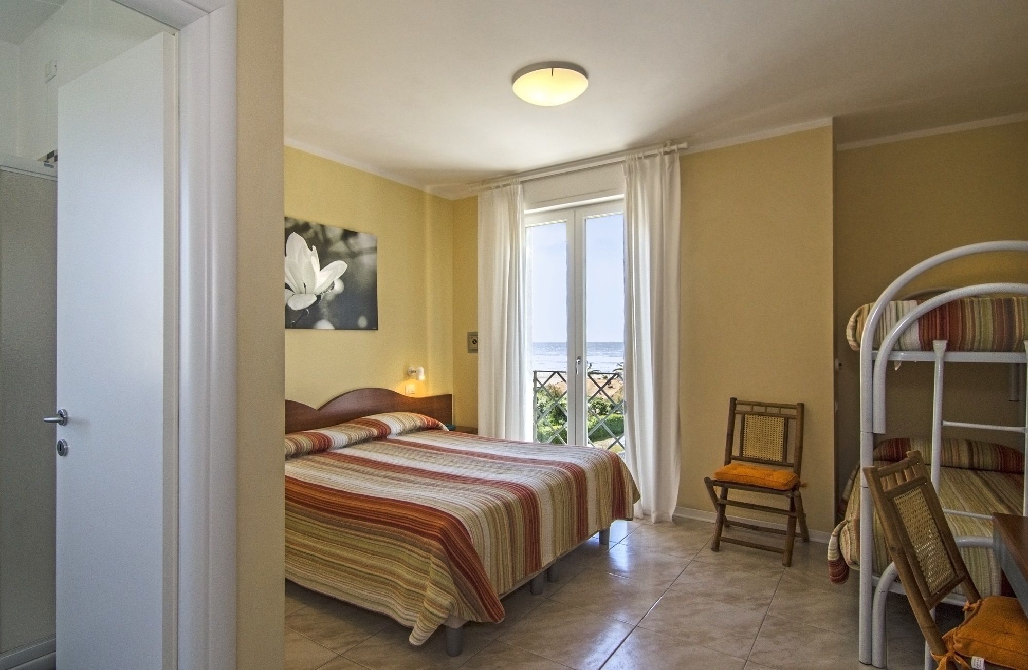 Une chambre à coucher avec un lit, une chaise, une fenêtre donnant sur un beau paysage et un luminaire au plafond.