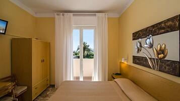 Een hotelkamer met een bed, een houten garderobe, een bureau met stoelen, een schilderij aan de muur en uitzicht op de omgeving.