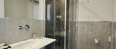 Un baño moderno con cabina de ducha de vidrio, un lavamanos grande y un inodoro.