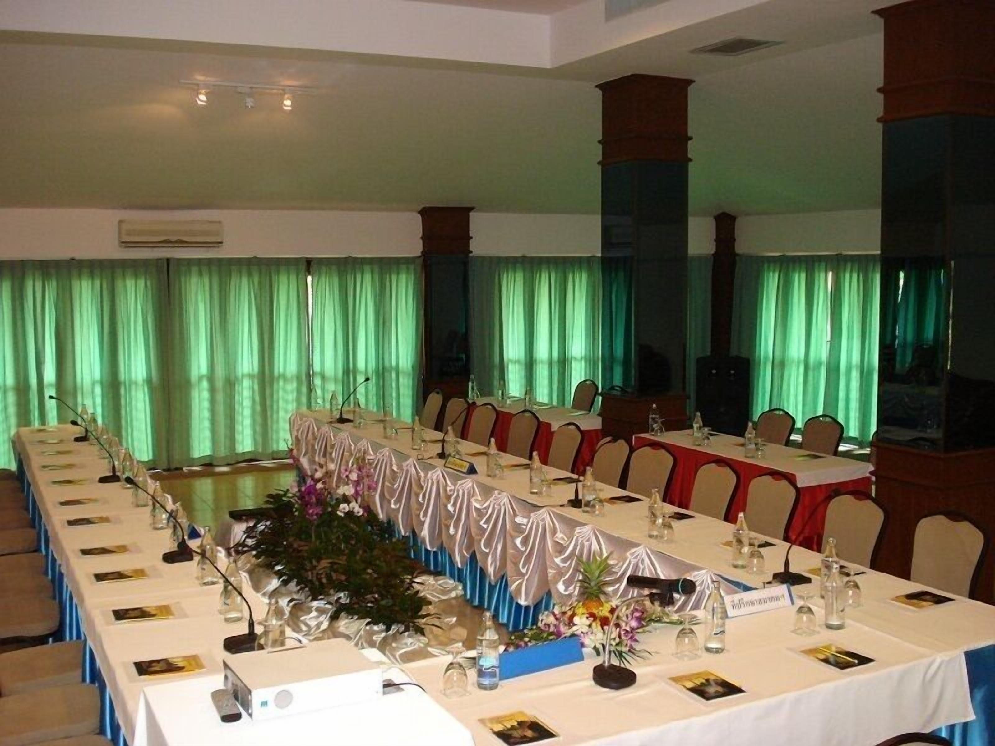 Un salón de conferencias con mesas largas, sillas y una zona de escenario.