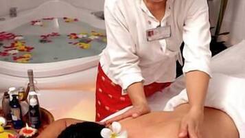 A massage therapy session in a spa setting with a client lying on a massage table and a therapist attending to them.