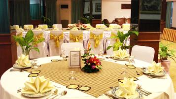 A round table set for a formal event with white tablecloths, gold sashes, and folded napkins.