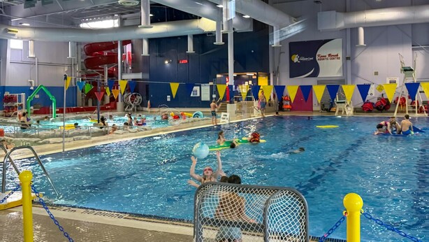 Una piscina interior con varias pistas de natación, un trampolín y un puesto de socorrista.
