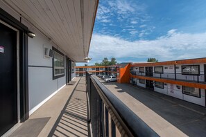 Un hotel con galería techada, estacionamiento al aire libre y varias edificaciones de diseño moderno.