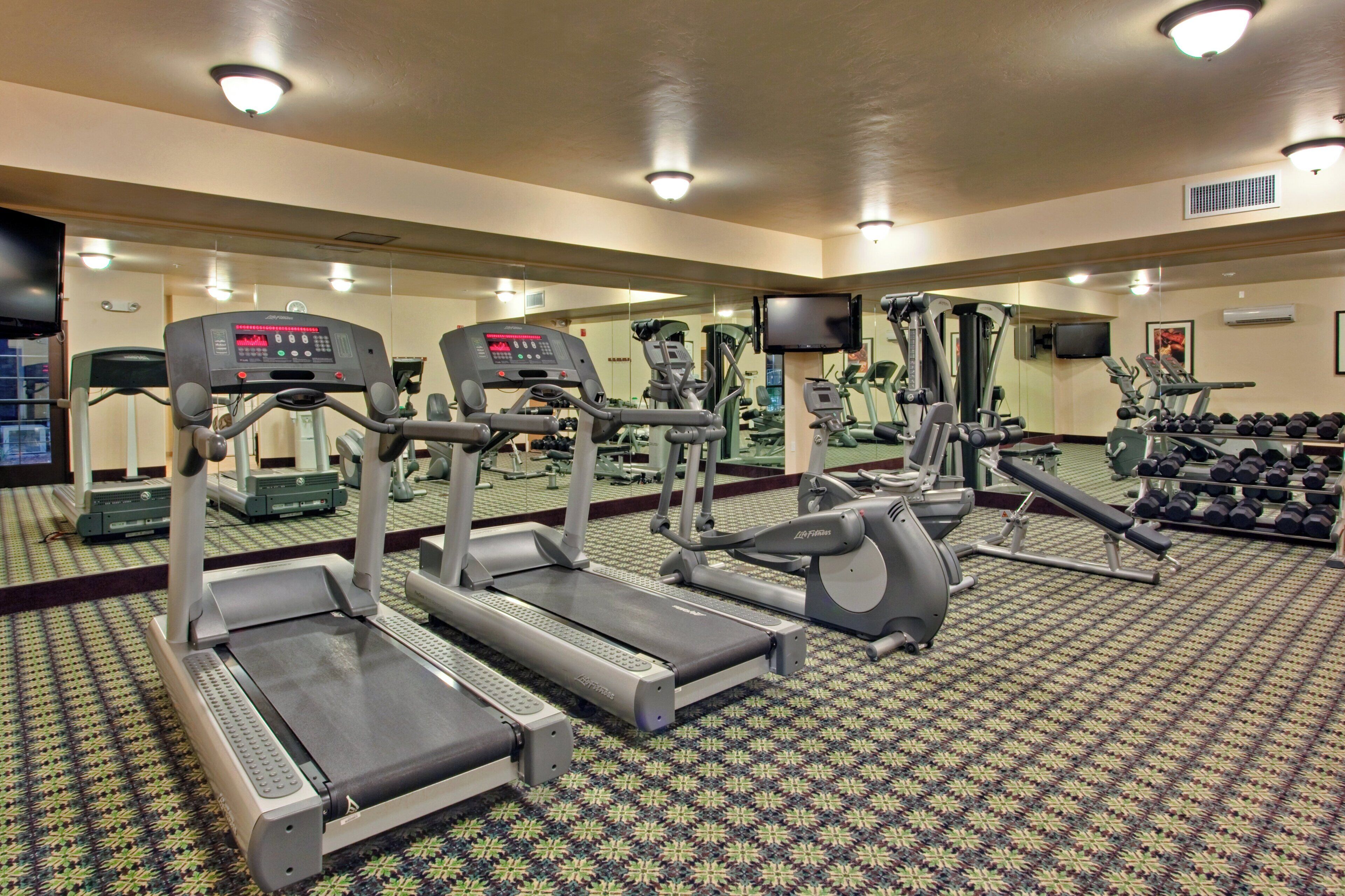 A gym with treadmills, elliptical machines, and free weights.