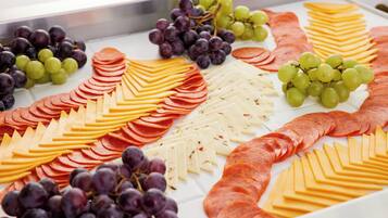 Una tabla de embutidos con carnes frías, quesos y uvas.