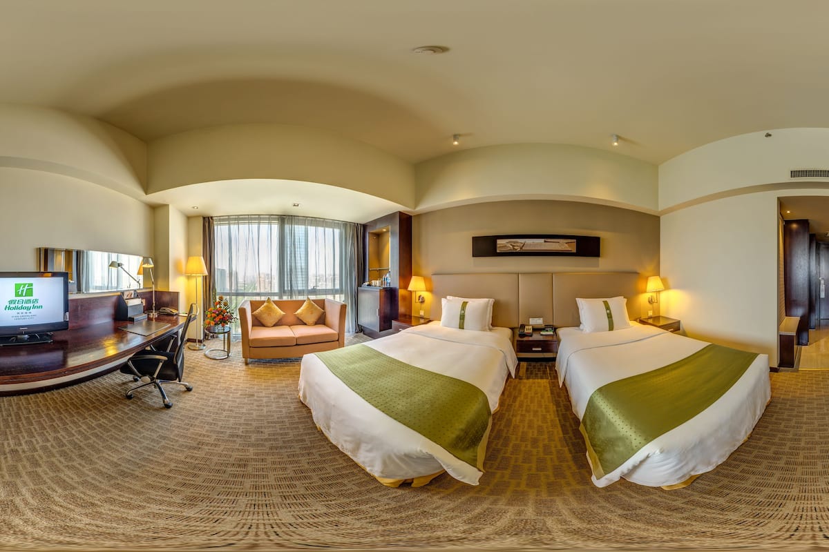 Ein Hotelzimmer mit Schreibtisch, zwei Betten, einer Couch und einem Fernseher.