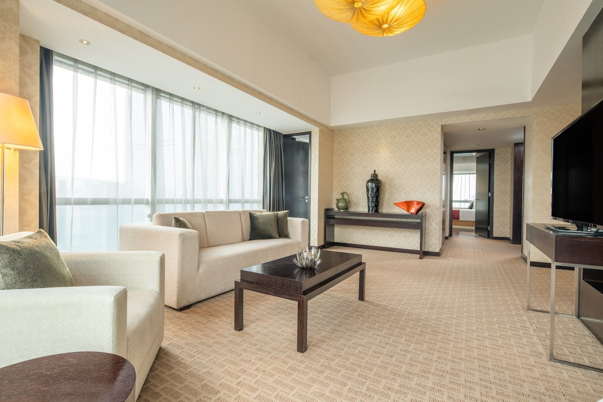 Ein modernes Hotelzimmer mit einer Couch, einem Couchtisch und einem Fernseher.