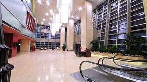 Un hall amplio con mostrador de recepción, zona de estar y una escalera mecánica.