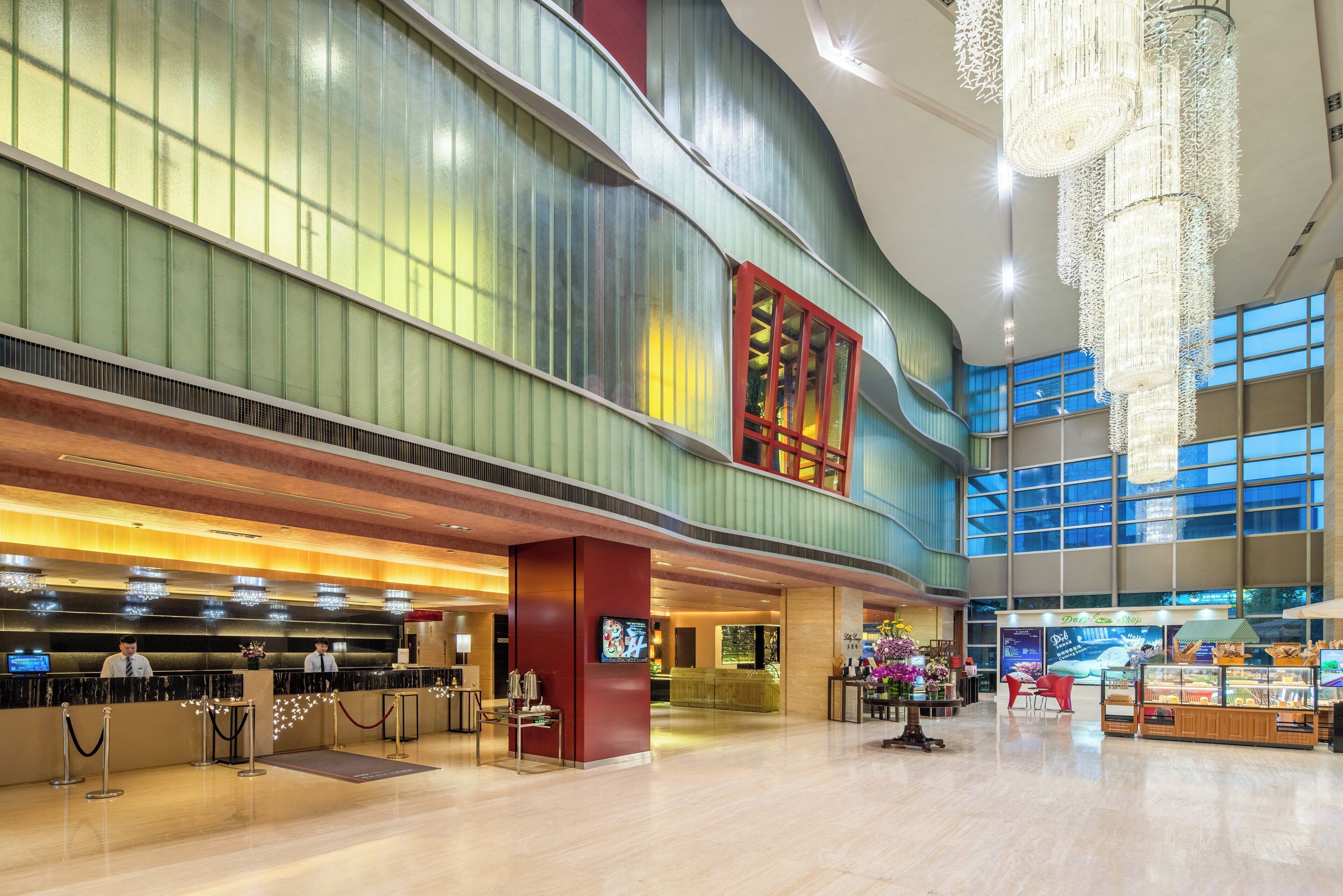 A spacious lobby with a reception desk, a chandelier, and a food display.