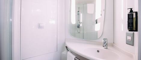 Un baño moderno con lavamanos blanco, espejo y ducha.