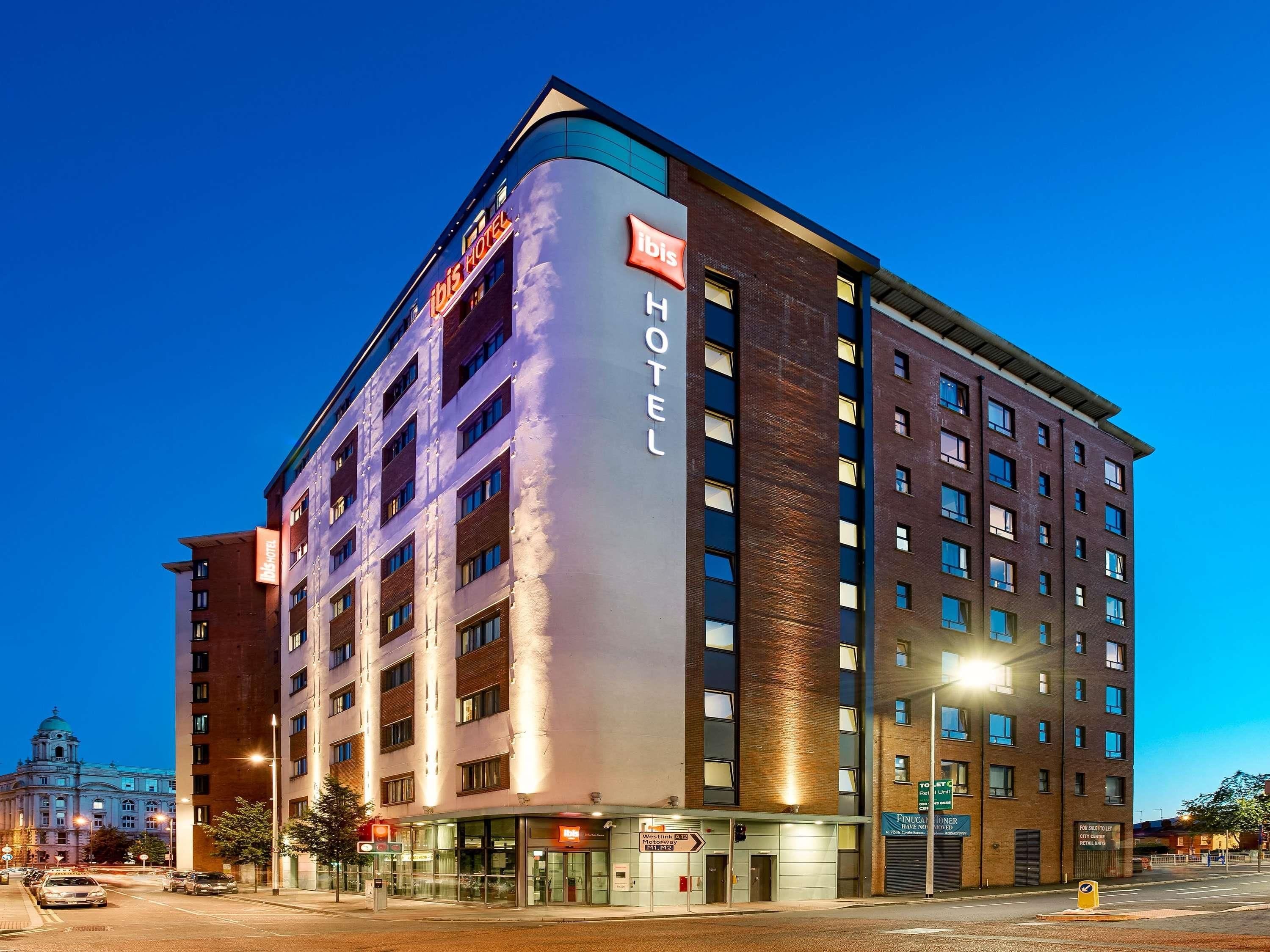A hotel with a modern design, featuring a prominent 'Ibis Hotel' sign, multiple floors, and a corner location.