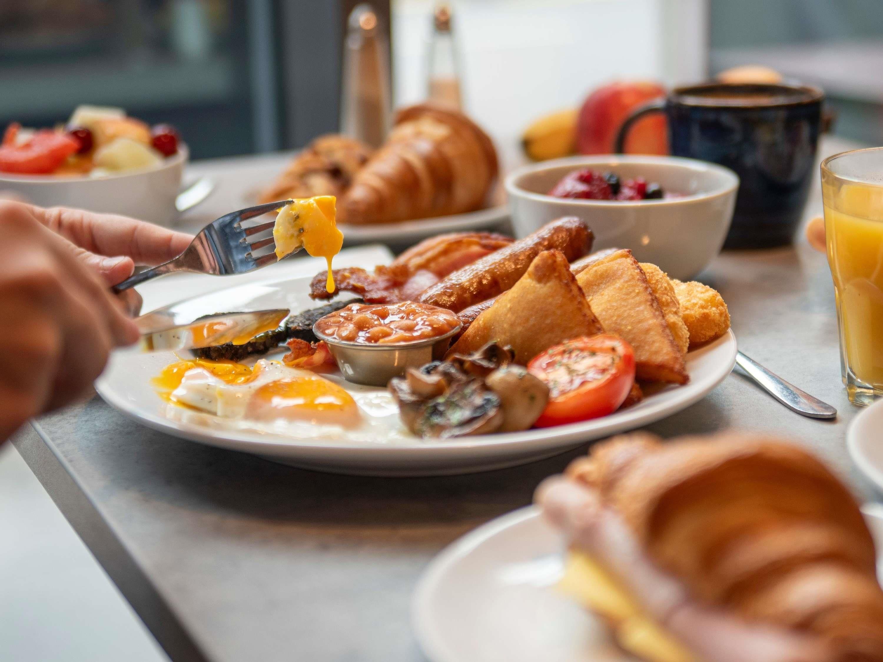 A breakfast plate with eggs, mushrooms, tomatoes, beans, toast, and bacon.