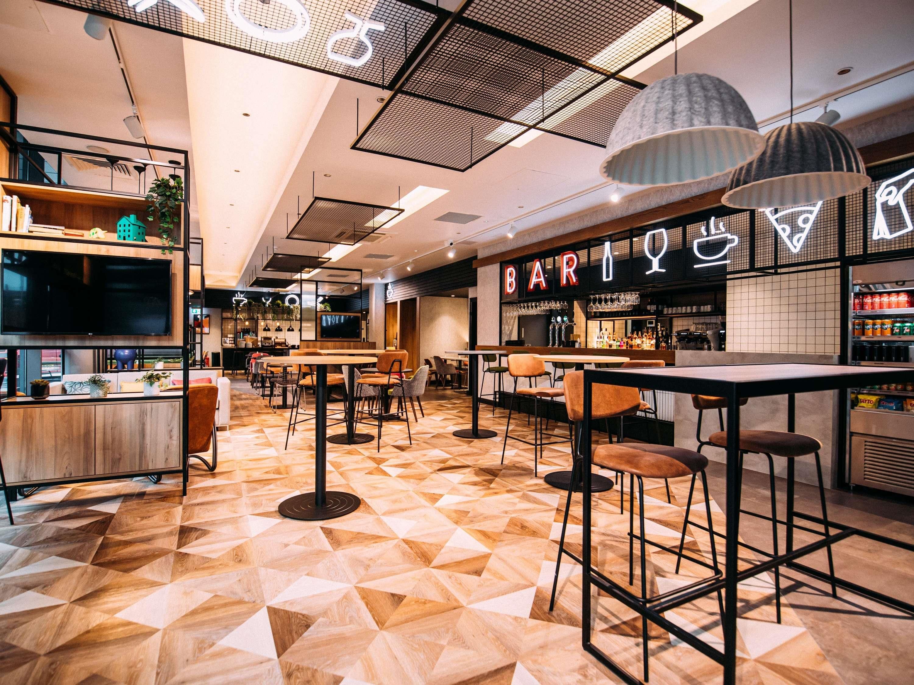 A modern bar area with geometric patterned flooring, bar stools, and pendant lighting.