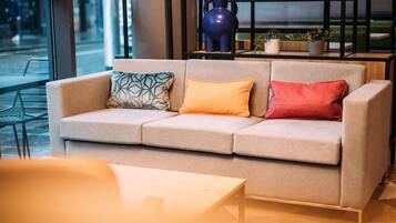 Un interior moderno con un sofá, una mesa y un estante con objetos decorativos.