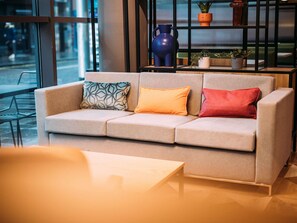 A modern interior with a sofa, a table, and a shelf with decorative items. - ibis Belfast City Centre (Belfast)