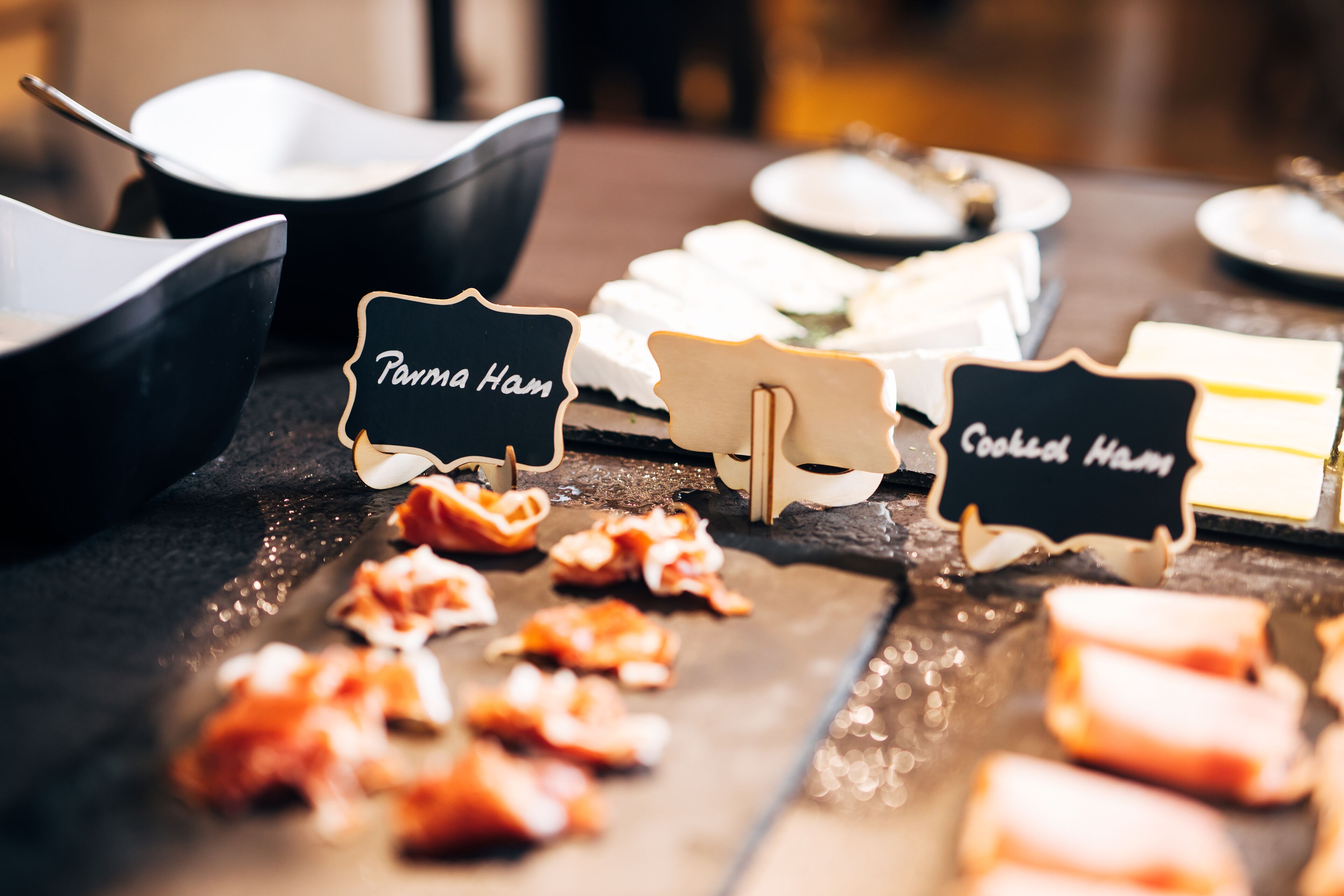 A buffet table with various food items and labeled signs indicating different dishes.