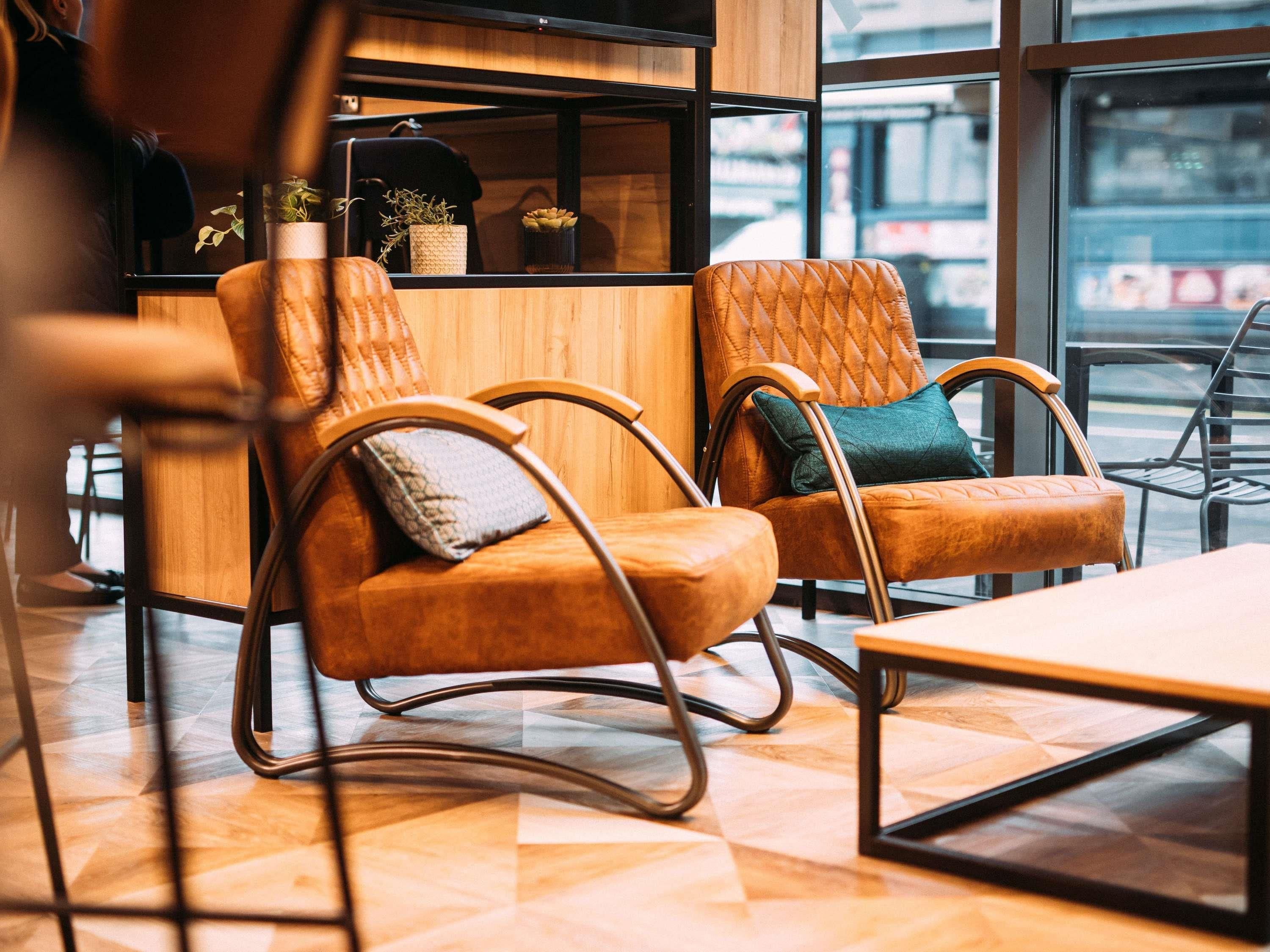 Un espace détente avec des fauteuils confortables, une table en bois et une vue dégagée grâce à de grandes fenêtres.