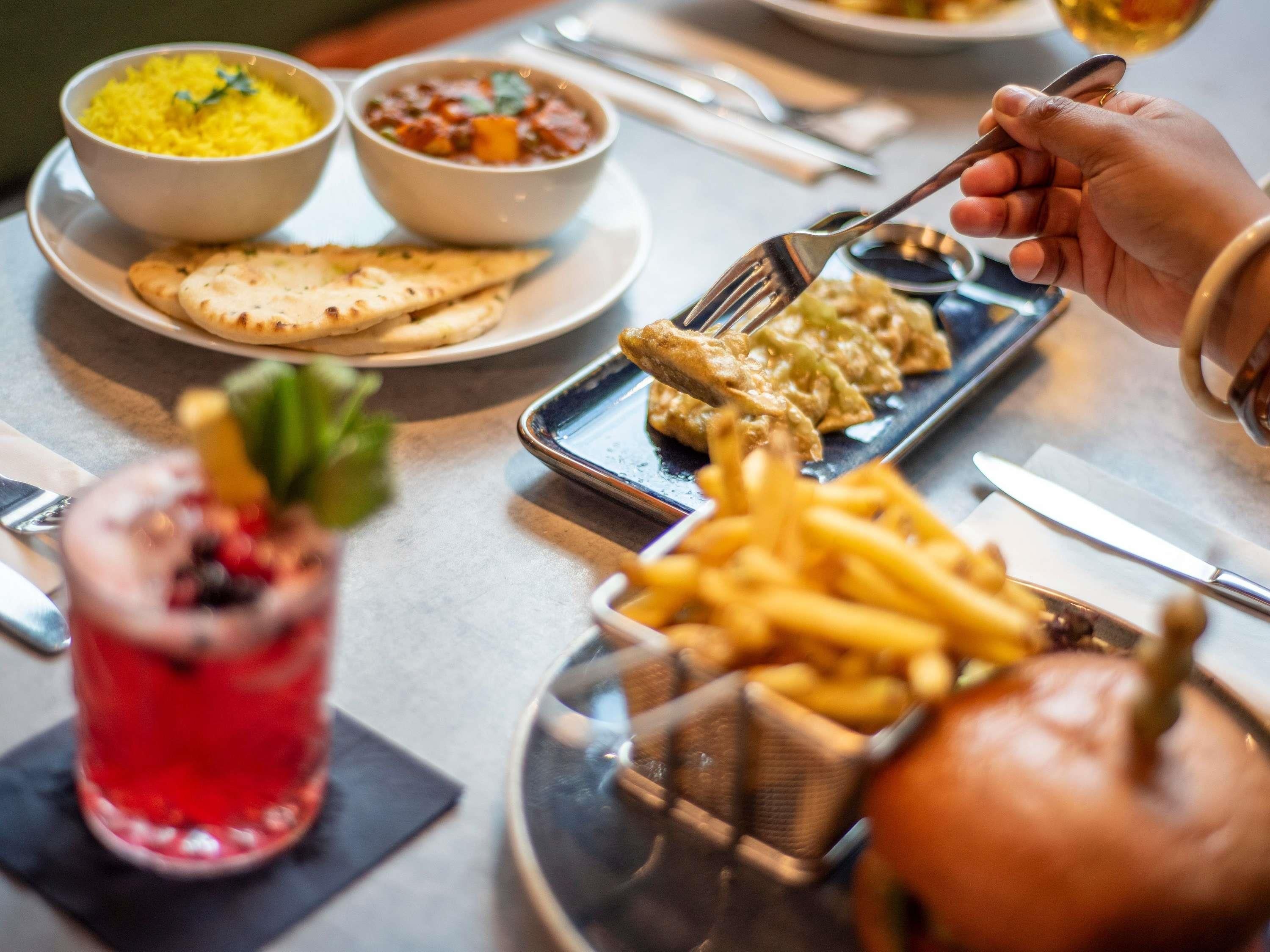 Une table à manger avec différents plats, notamment du riz, de la soupe et du pain, ainsi qu’un hamburger et des frites.