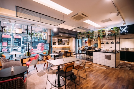 A modern cafe with a mix of seating options, including tables and chairs, and a visible kitchen area.