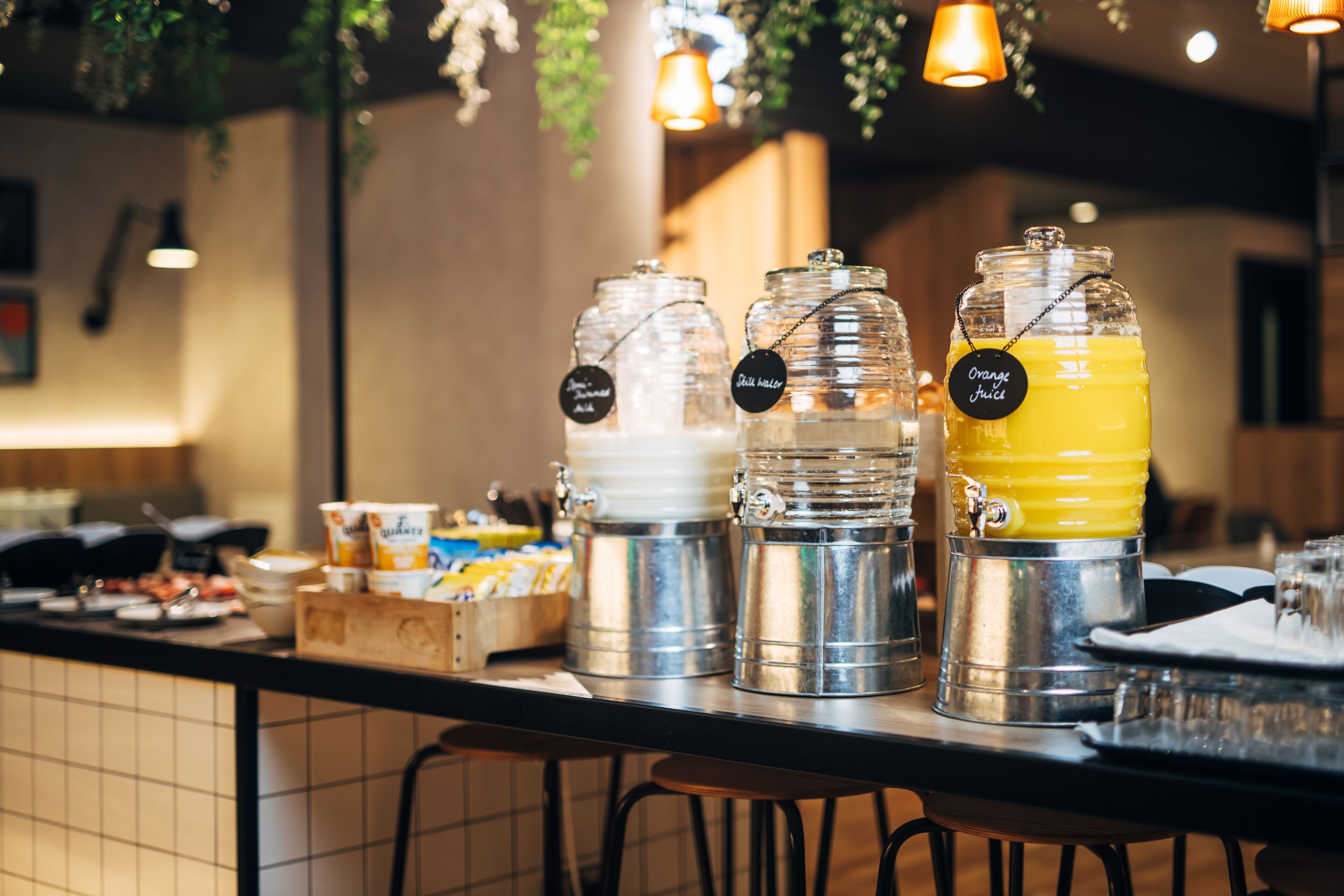A buffet bar with various food and drink dispensers, including a juice dispenser labeled "Orange Juice."