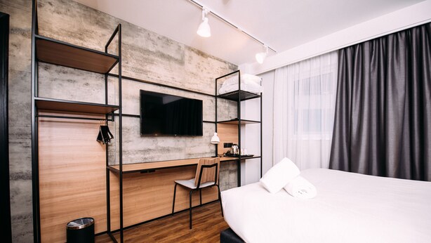 A modern hotel room with a bed, desk, chair, and TV. - ibis Belfast City Centre (Belfast)
