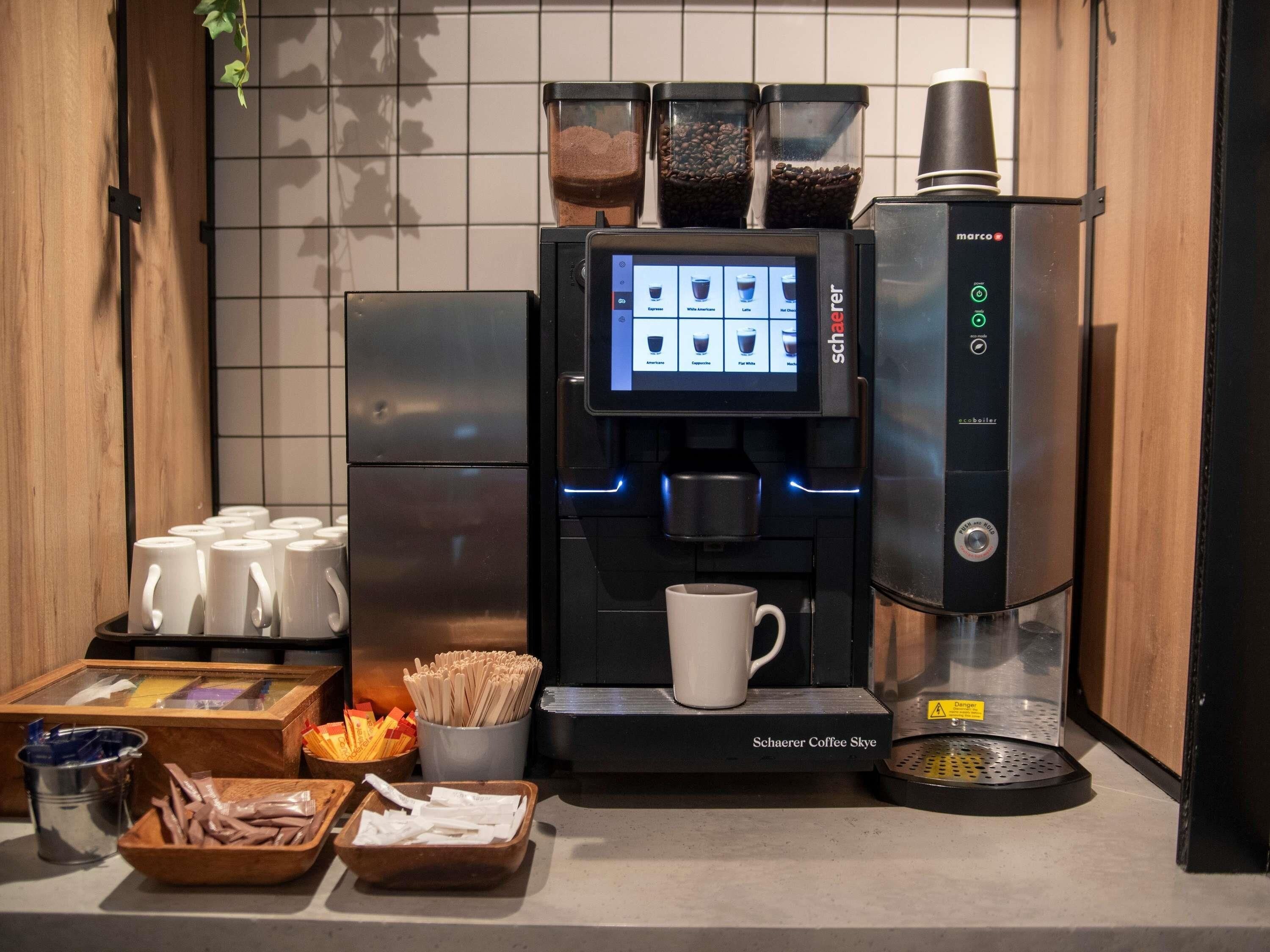 A coffee machine with a digital display, coffee pods, and a cup.
