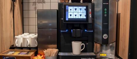A coffee machine with a digital display, coffee pods, and a cup.