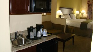 A compact hotel room with a kitchenette, a bed, and a small seating area. - Holiday Inn Express Hotel & Suites Brownfield by IHG (Brownfield)