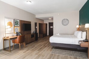 A hotel room with a bed, desk, chair, TV, and a decorative wall piece. - Holiday Inn Hou Energy Corridor Eldridge by IHG (Houston)