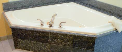 Une baignoire rectangulaire dotée de trois robinets, placée sur un plan de travail en granit foncé.
