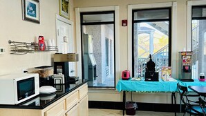 A kitchen with a microwave, coffee maker, and a table with a blue tablecloth. - Magnolia Inn And Suites (Magnolia)
