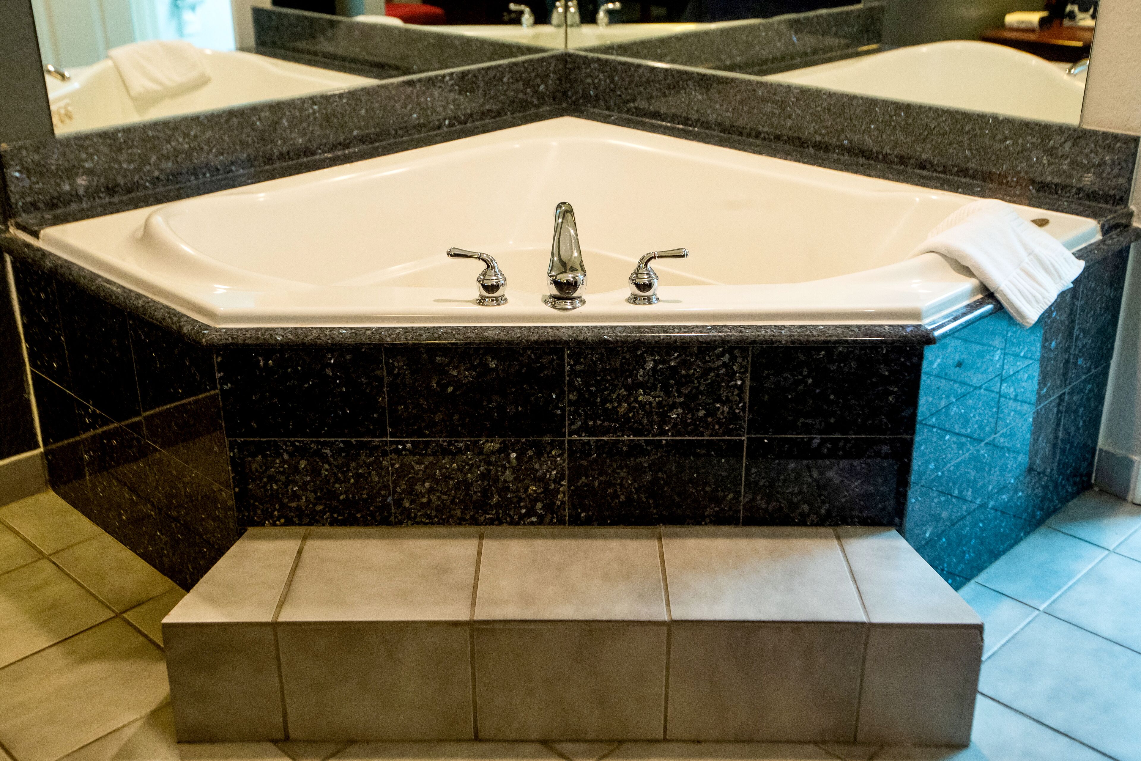 A bathroom with a large freestanding bathtub, a mirror above the sink, and a towel on the edge of the tub.