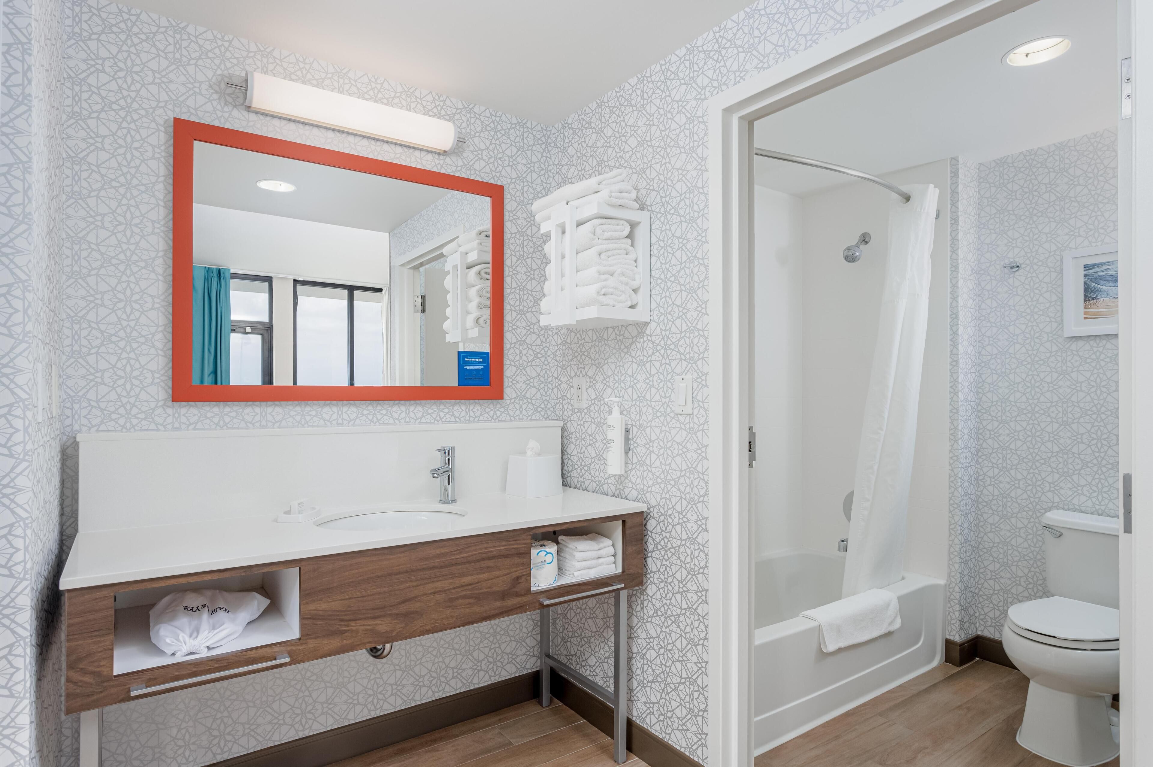A modern bathroom with a white sink, mirror, and shower.